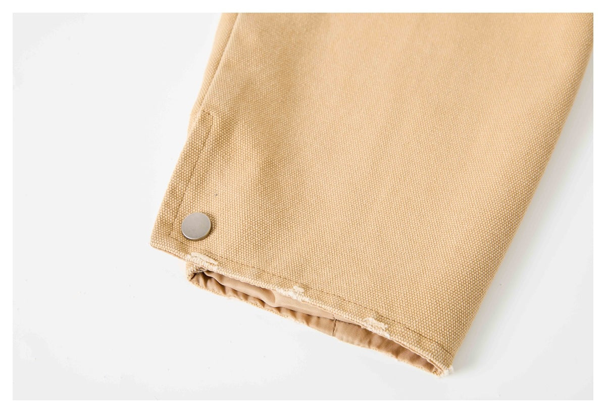 Tan woven garment cuff with a round metal snap and visible lining.