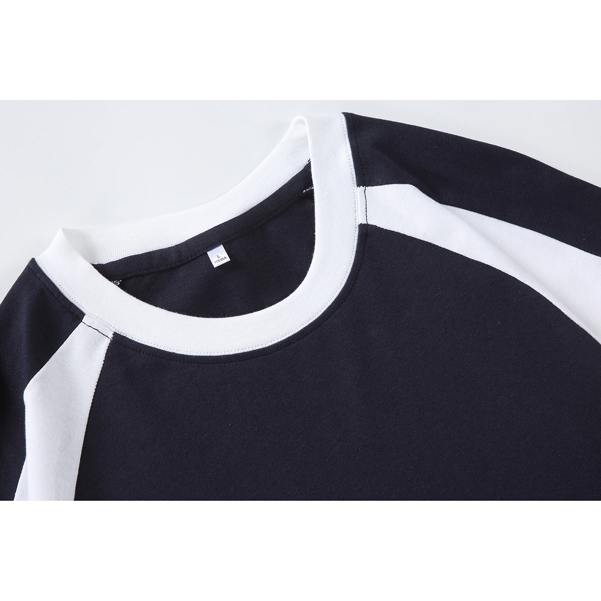 Close-up of a navy T-shirt with a white crew neck and white raglan sleeve panels.
