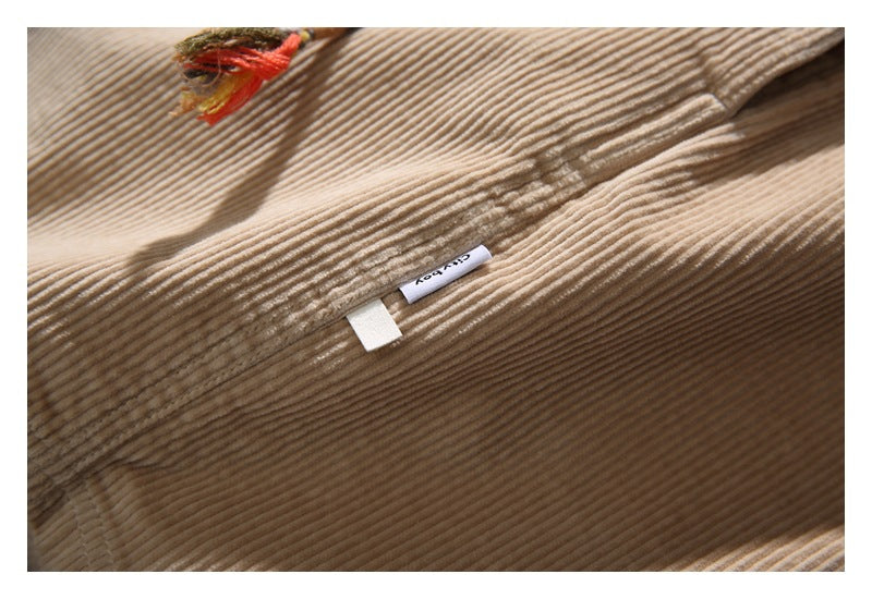 Close-up of beige ribbed corduroy with a seam, loose threads, and a small white label.