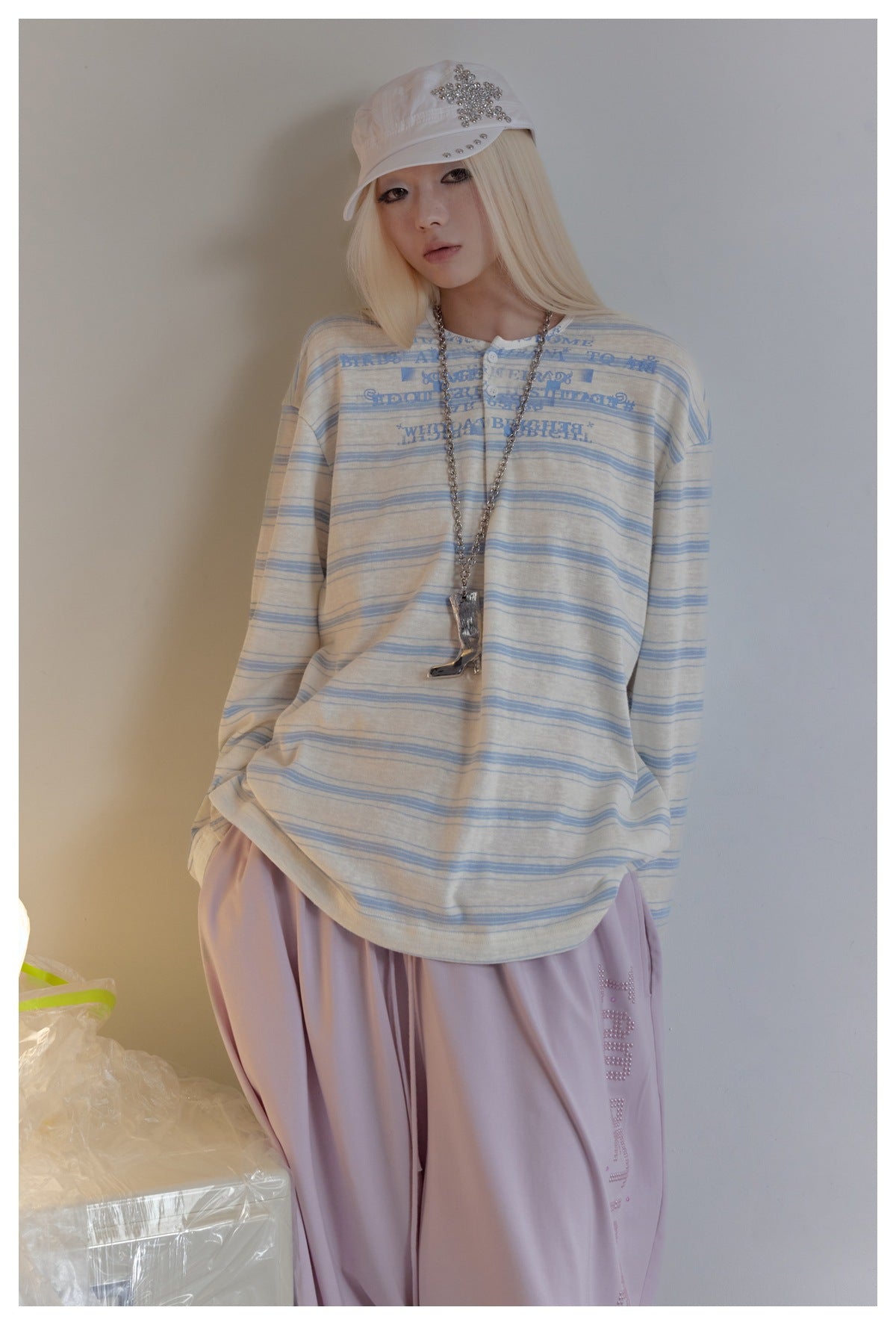 Close view of model wearing oversized blue striped henley top with button placket and blue print, with lilac pants