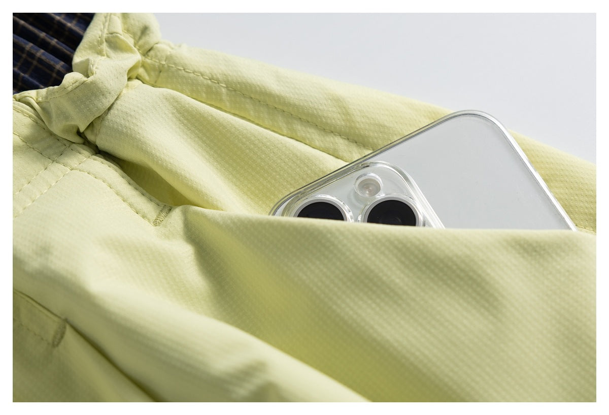 Close-up of a phone tucked into a pocket on the pale yellow garment, beside the elastic waistband.