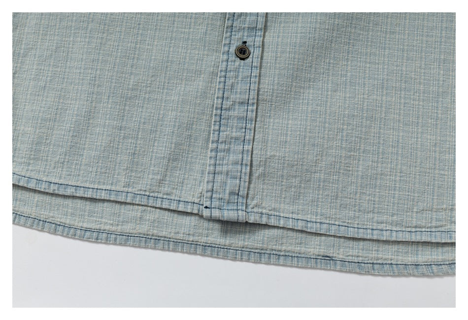 Close-up of the lower hem and button placket of a light blue patterned shirt.