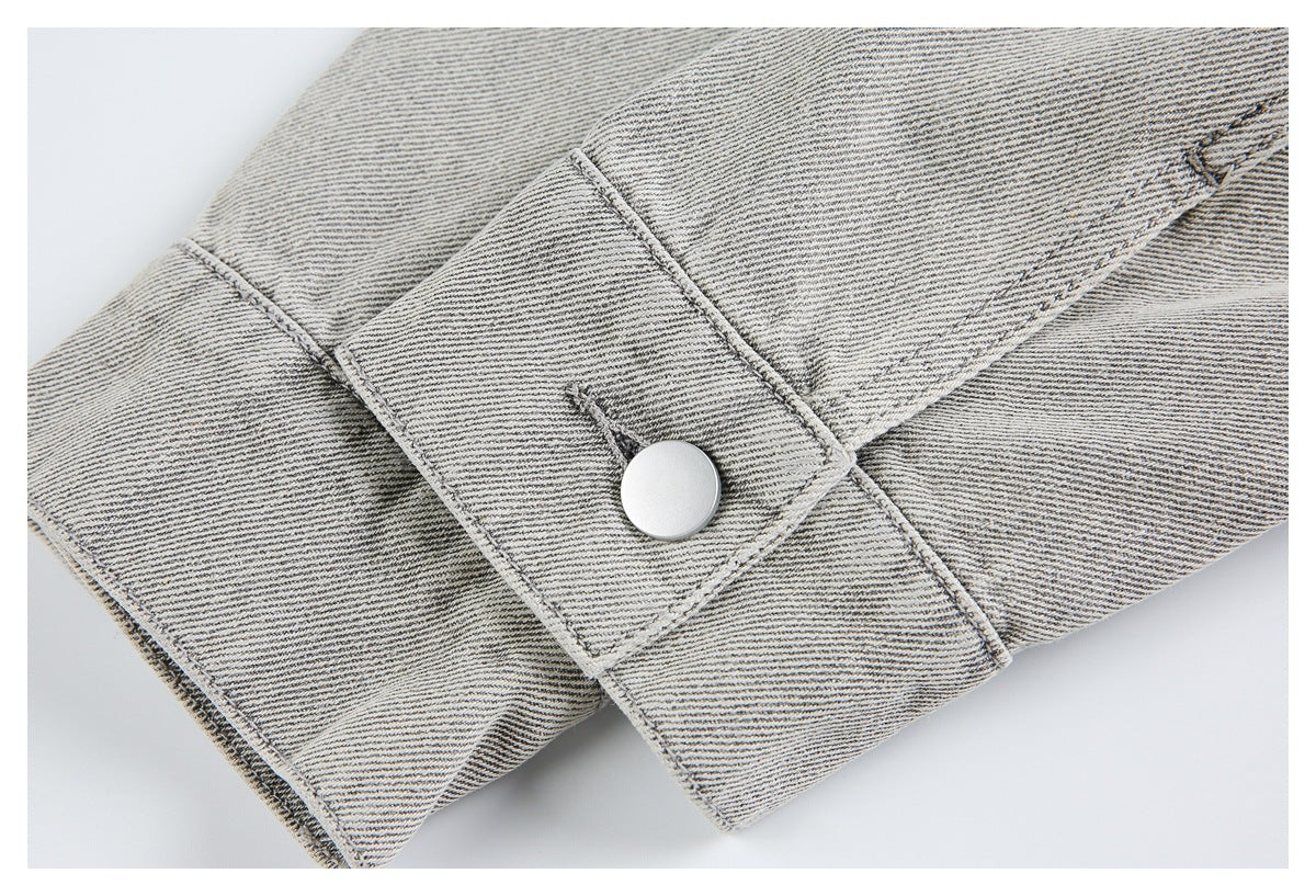 Close-up of a light gray denim cuff with a silver button and visible stitching.