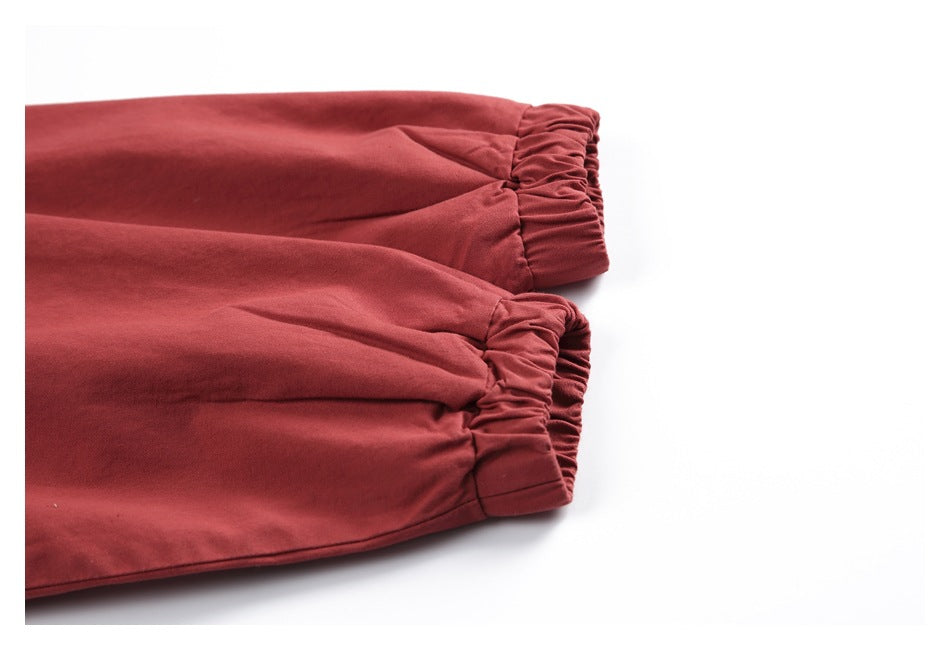 Close-up of two brick-red jacket sleeves ending in gathered elastic cuffs.
