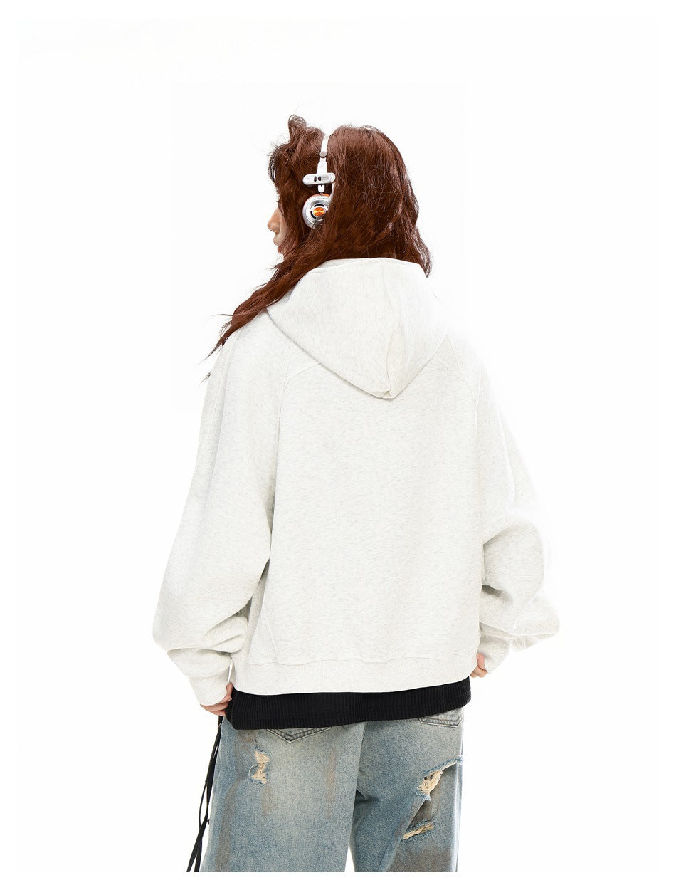 Rear view of a model wearing a light cream oversized hooded sweatshirt with jeans.