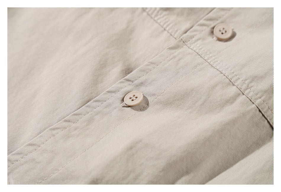 Close-up of two beige buttons and stitched seams on a light khaki garment.