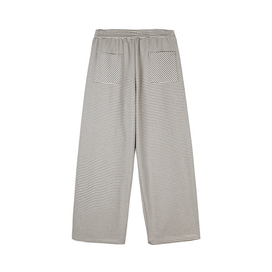 Flat-lay of cream wide-leg pants with thin black horizontal stripes, an elastic waist and two front pockets.