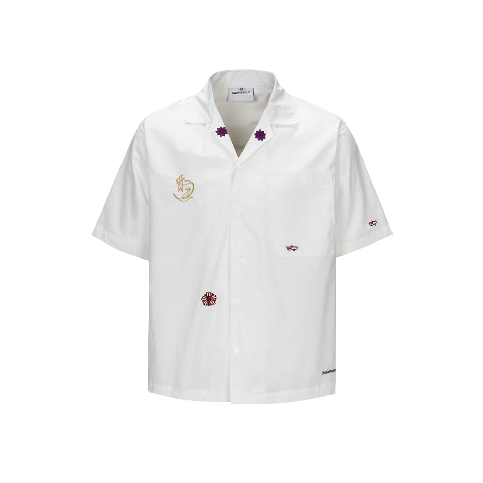 White short-sleeve camp collar shirt with chest pocket and embroidered motifs, front view