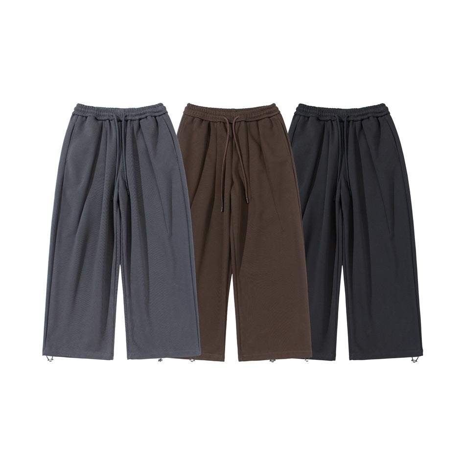Three pairs of wide-leg drawstring pants shown from the front in gray, brown and black.