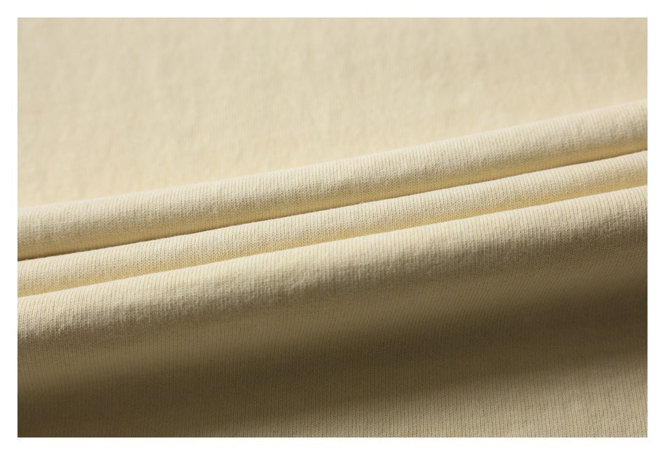 Close-up of pale cream fabric folded to show its knit surface and edge.