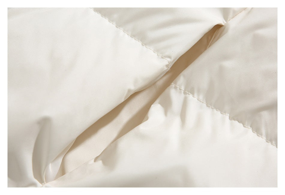 Close-up of cream jacket fabric with a folded edge and stitched seam.