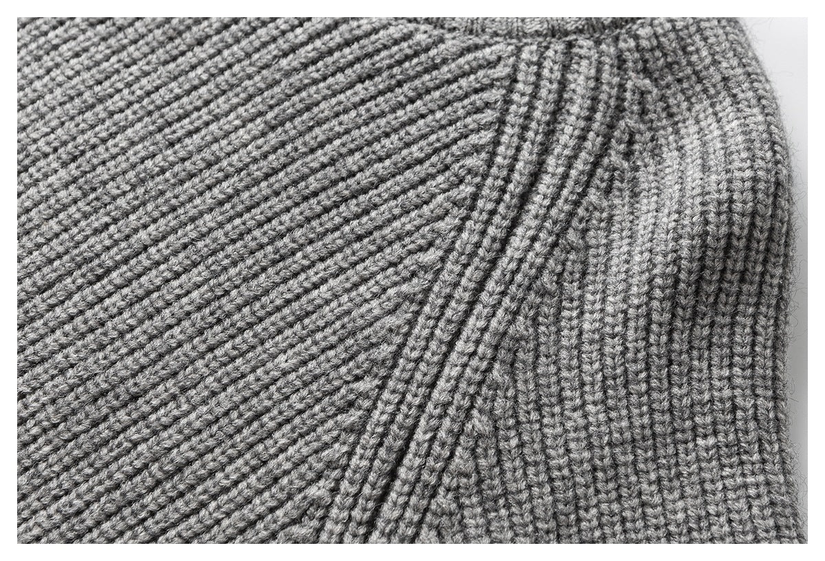 Close-up of light gray ribbed knit fabric showing a curved seam and textured stitches.
