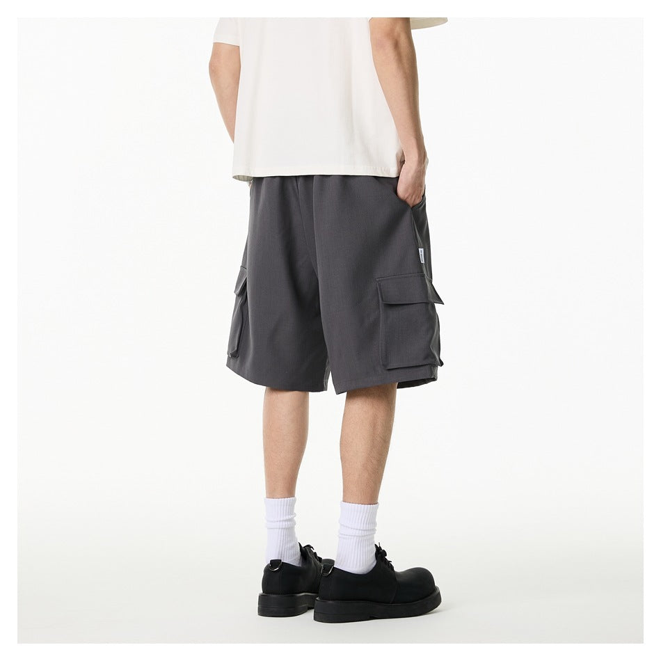 Rear view of a model wearing charcoal-gray cargo shorts with large flap pockets on both sides.