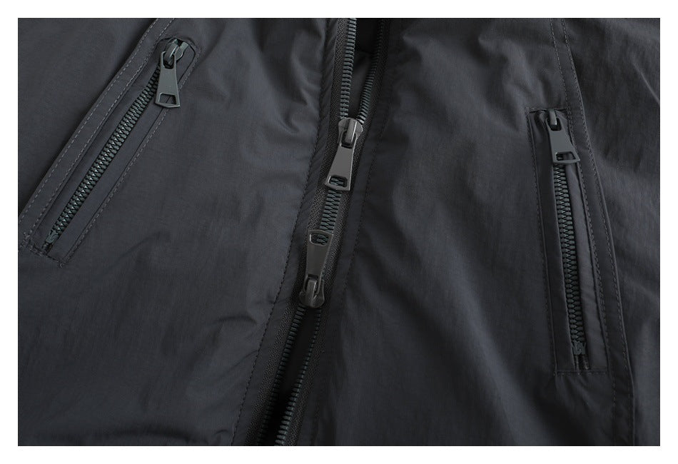 Close-up of a black jacket front with a central zipper and two vertical zip pockets.