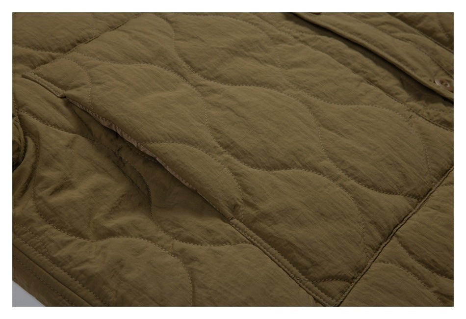 Close-up of olive-brown quilted jacket panels, stitching, and part of the button placket.