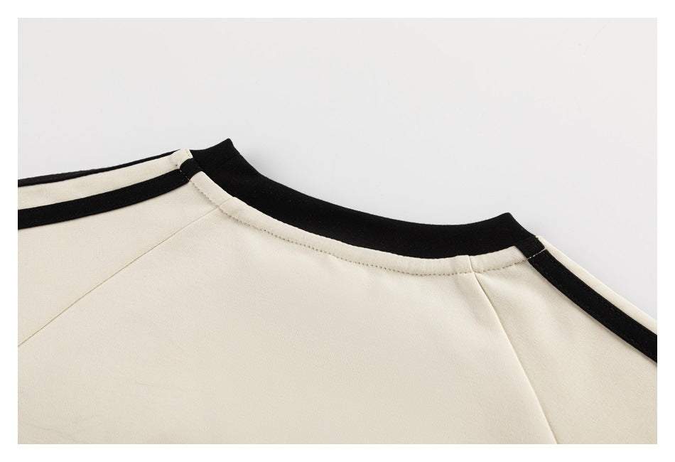 Close-up of a cream garment's neckline with black ribbed trim and black shoulder stripes.