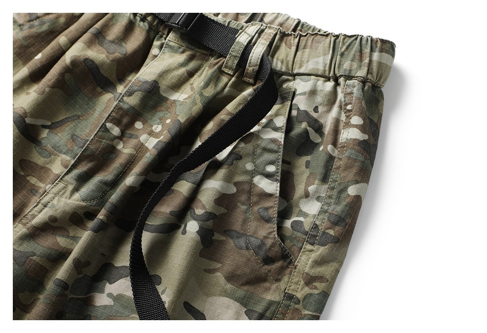 Close-up of a side pocket, elastic waistband, and black belt on olive camouflage pants.