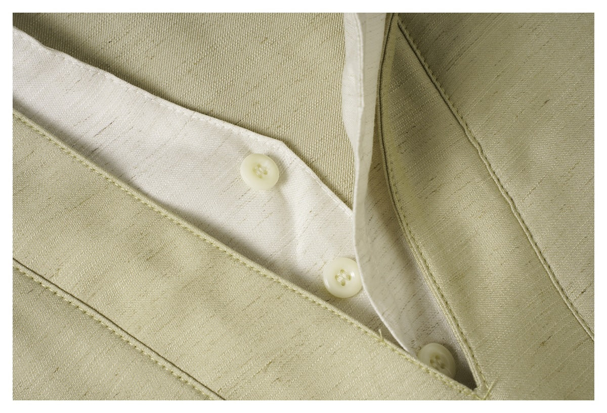 Close-up of the pale olive-beige garment's button placket, pale buttons, and stitched seams.