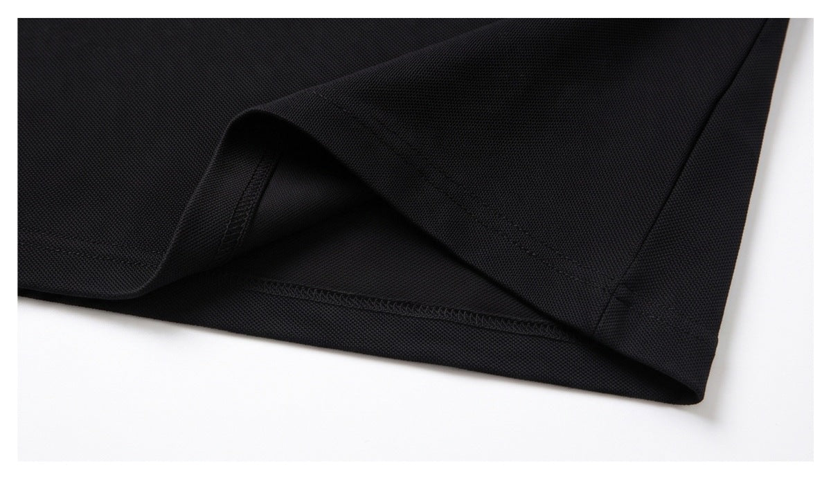 Close-up of a black garment hem showing the side seam and stitched edge.