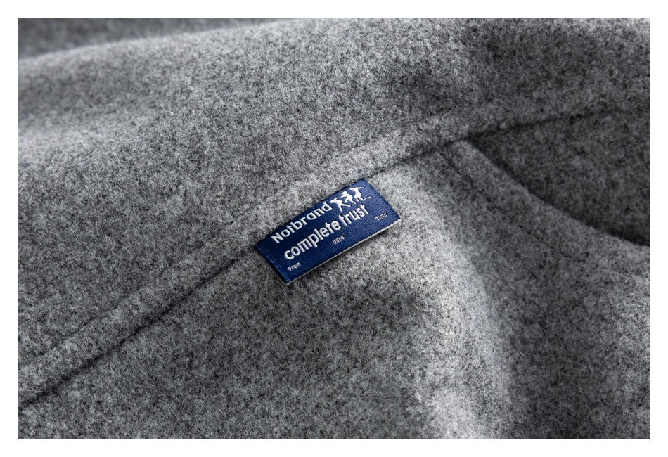 Close-up of a blue sewn-in label on the gray coat, with English lettering.