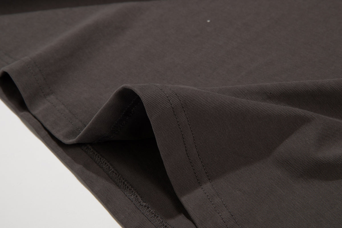 Close-up of a dark brown garment hem, showing double stitching and the inside overlocked seam.