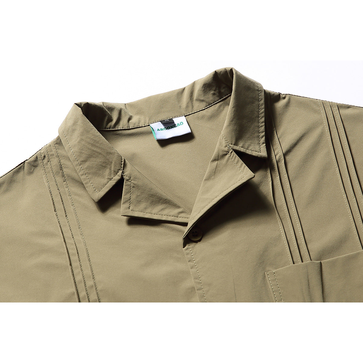 Close-up of the olive shirt's pointed collar, button placket, stitching, and inner neck label.