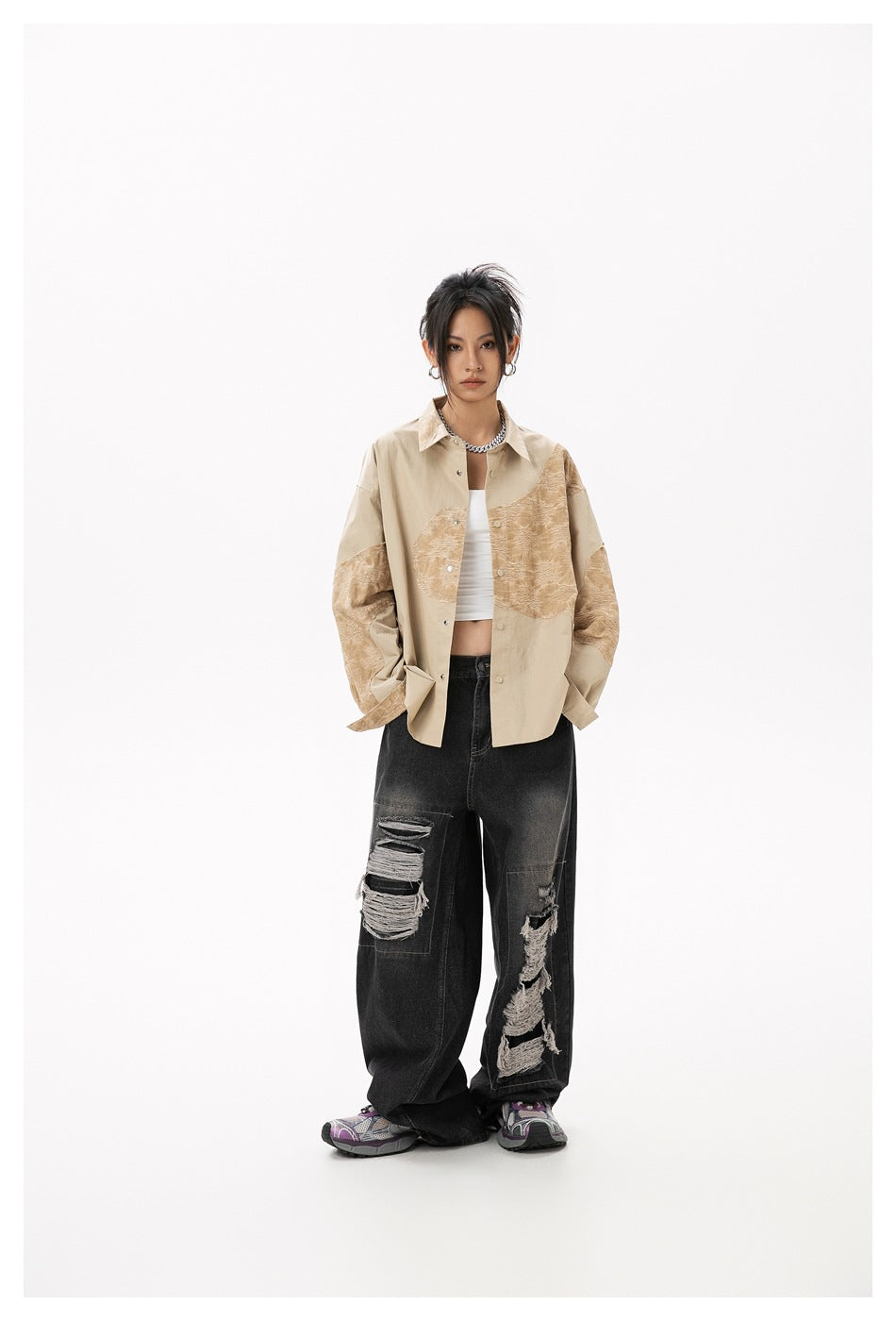 Model wearing the yellow patchwork shirt open over a white top with black ripped jeans, front view