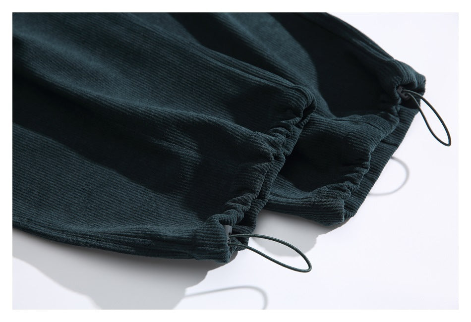 Close-up of dark teal pants with gathered hems and adjustable drawstring loops.