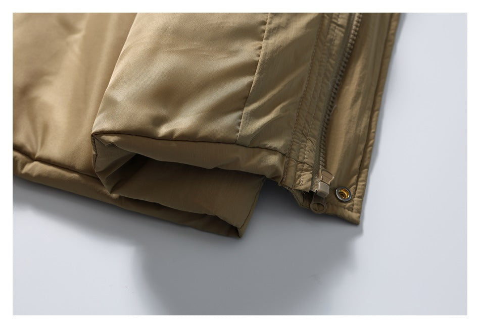 Close-up of a tan padded jacket hem with a zipper, snap, and gathered cuff-like edge.