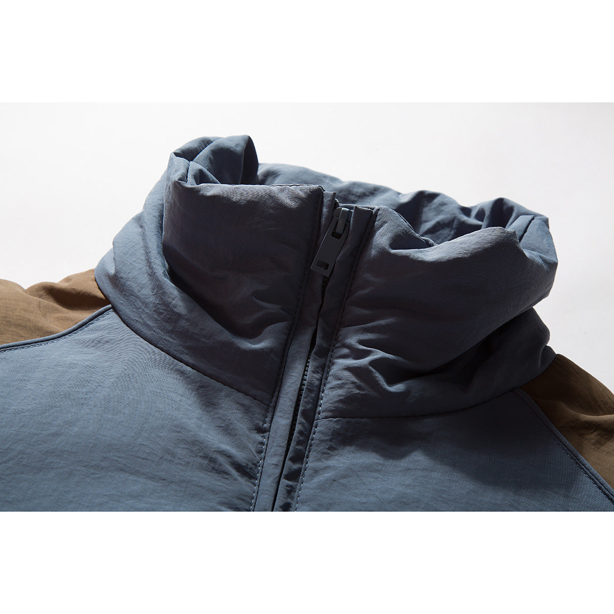 Close-up of a slate-blue jacket collar and front zipper, with brown fabric visible behind it.