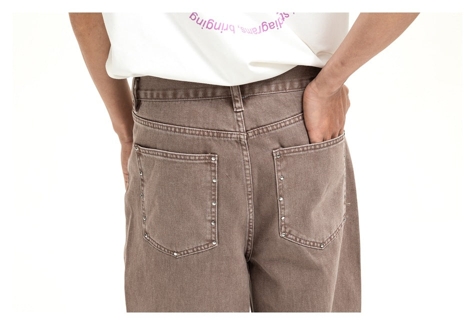 Close-up of the taupe jeans' waistband and two large back pockets with small metal studs along the edges.