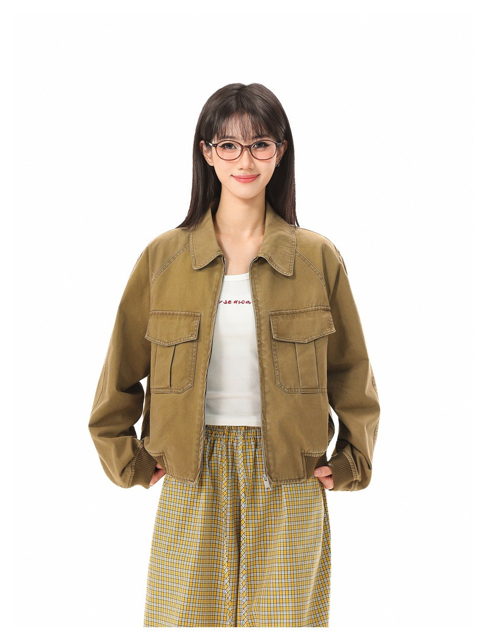 Front view of a model wearing an open tan collared jacket with flap pockets and ribbed cuffs, over a white top and plaid
