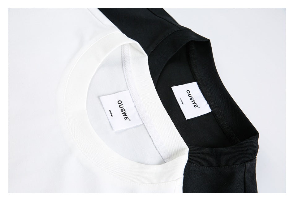 Close-up of the ribbed necklines and sewn-in labels of white and black sleeveless tops.