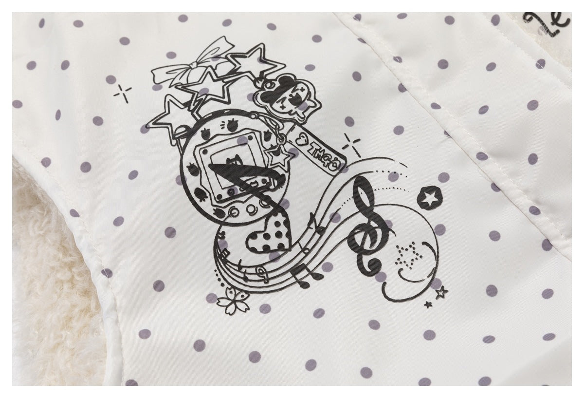 Close-up of an ivory, gray-dotted jacket with a black cartoon, stars, and music-note print.