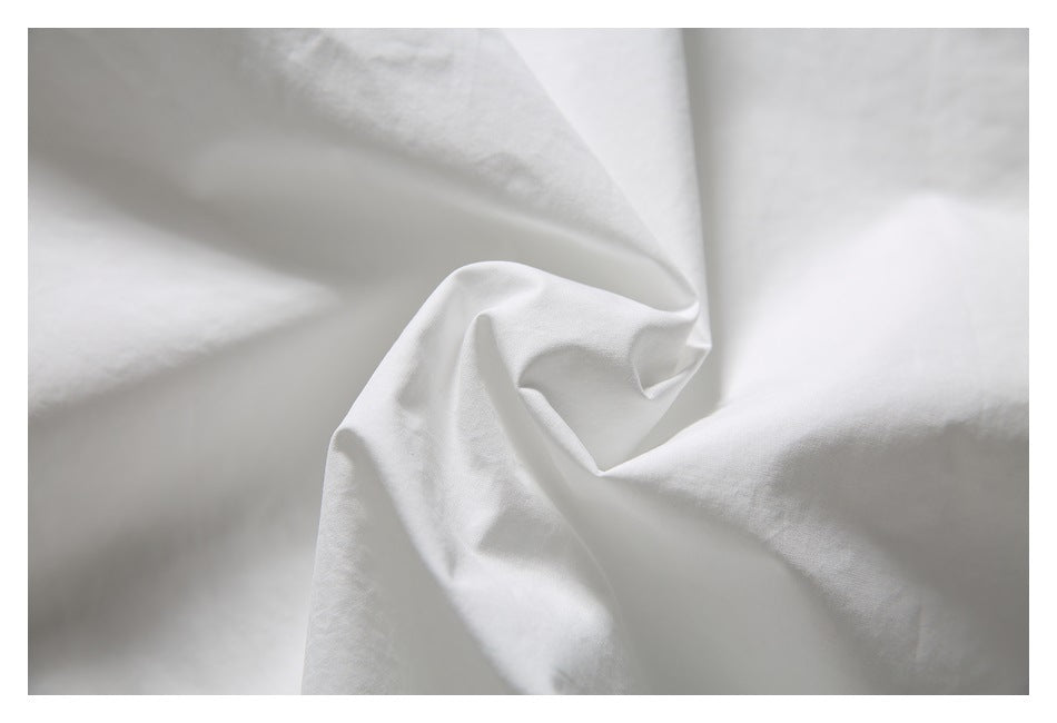 Close-up of white garment fabric gathered into soft folds, showing its surface and drape.