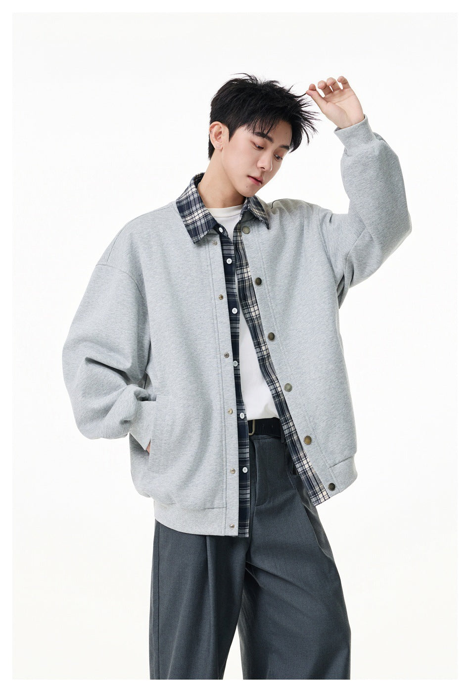 Model wearing an oversized light gray snap-front jacket over a dark plaid shirt and white tee.