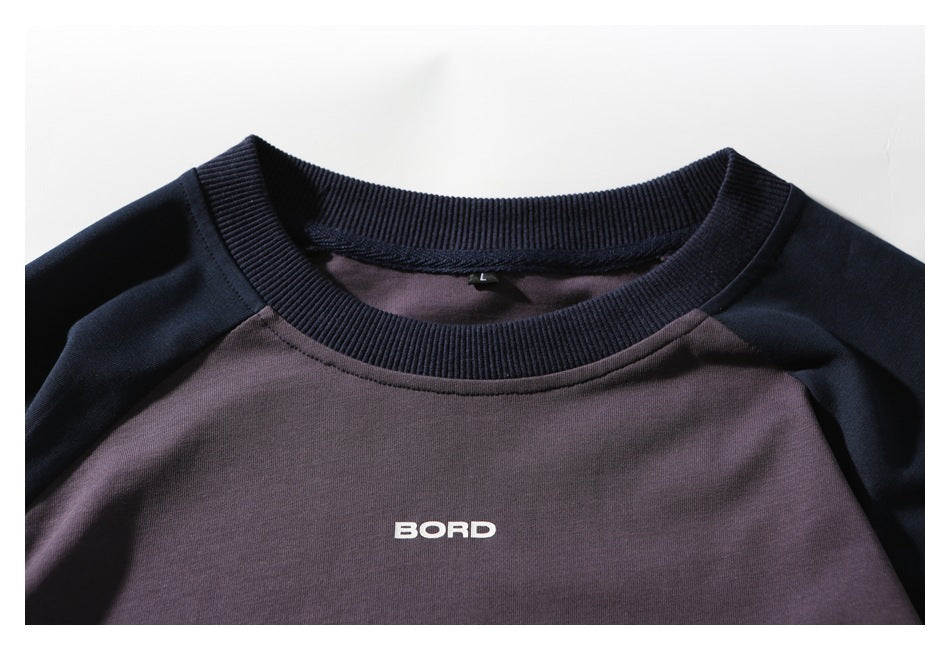 Close-up of the plum shirt front, showing its ribbed navy collar, raglan seams, and white BORD lettering.