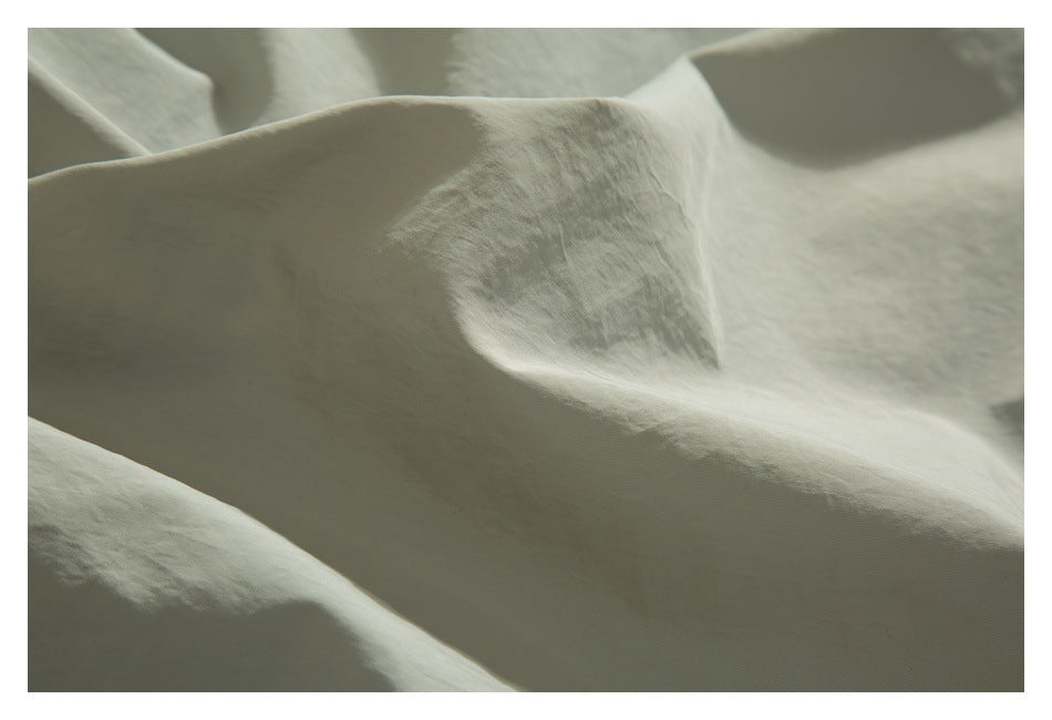 Extreme close-up of pale sage garment fabric showing its surface texture and folds.