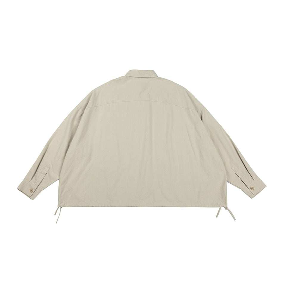 Back view of a loose light beige collared jacket with long sleeves, button cuffs and adjustable hem ties.