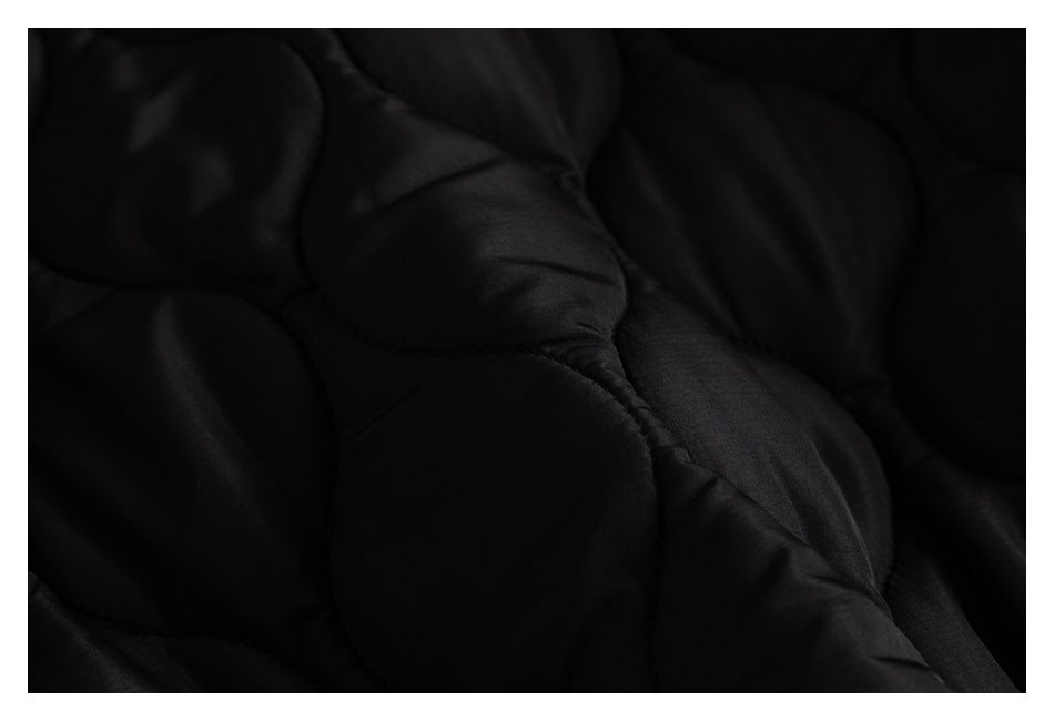 Close-up of black quilted fabric with curved stitched channels.