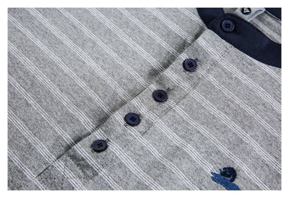 Close-up of a gray shirt with thin white stripes, navy buttons, and a small embroidered animal motif.