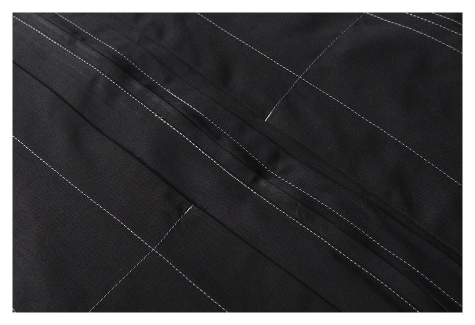 Close-up of black fabric with intersecting white contrast stitching and a raised seam.