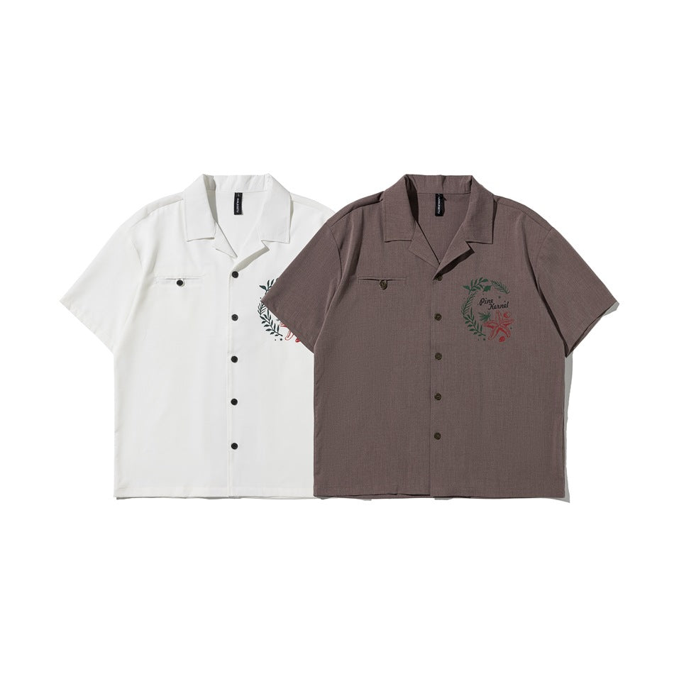Front view of white and brown short-sleeve shirts with notched collars, button fronts, chest pockets, and printed graphics.