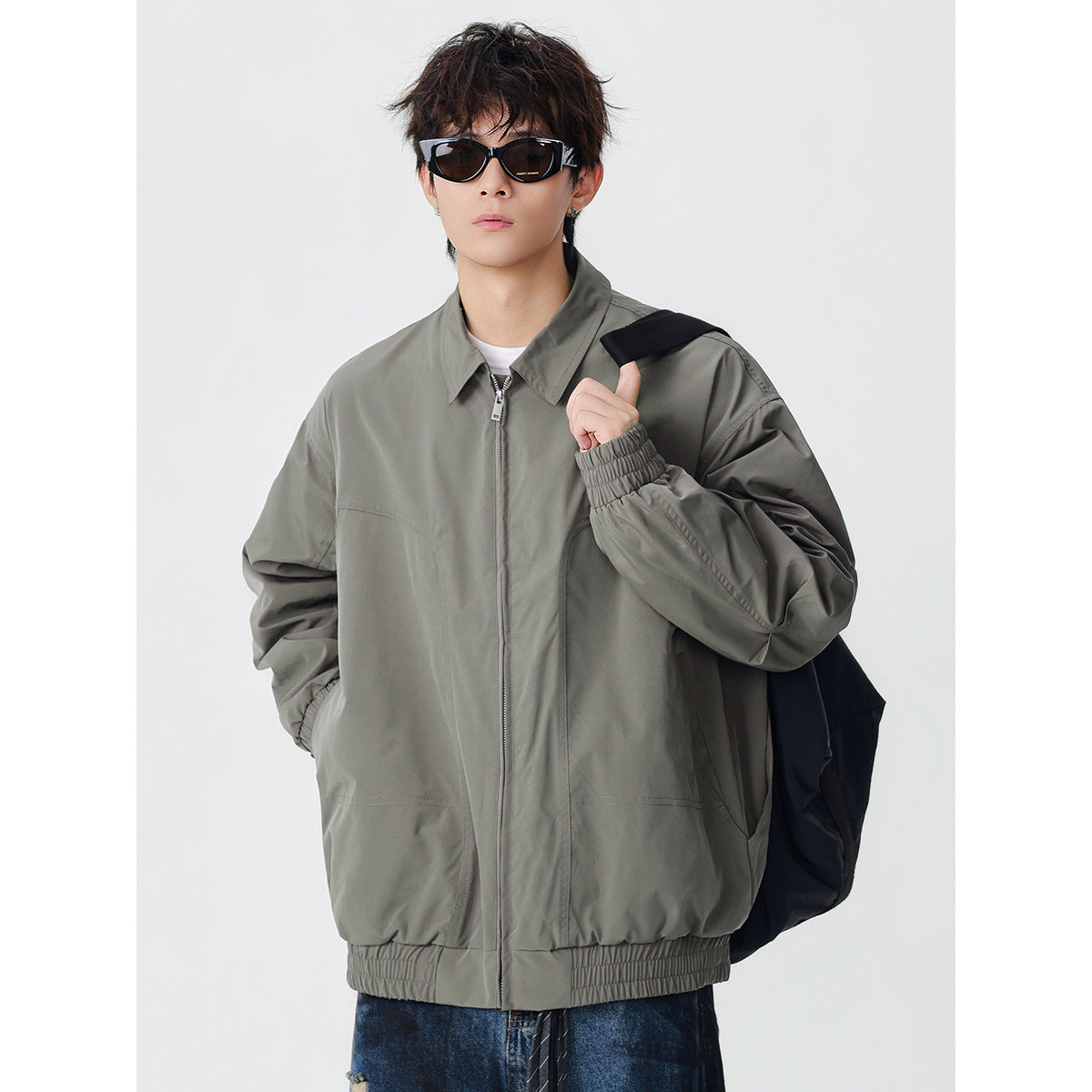 Model wearing a gray-green zip jacket with a pointed collar, elastic cuffs and hem, and front pockets.