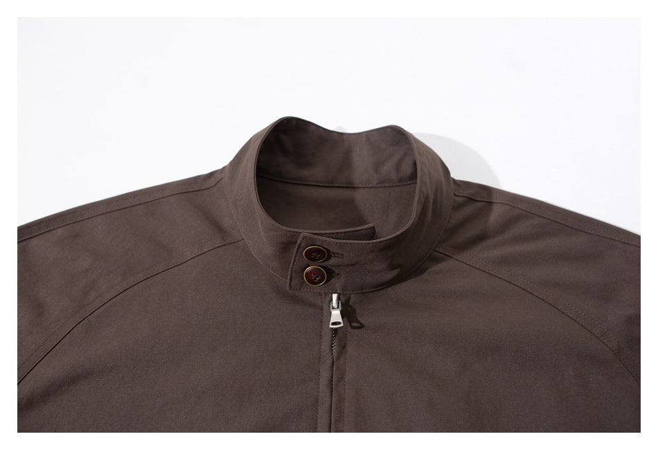 Close-up of the dark brown jacket's stand collar, button tab, and zipper.