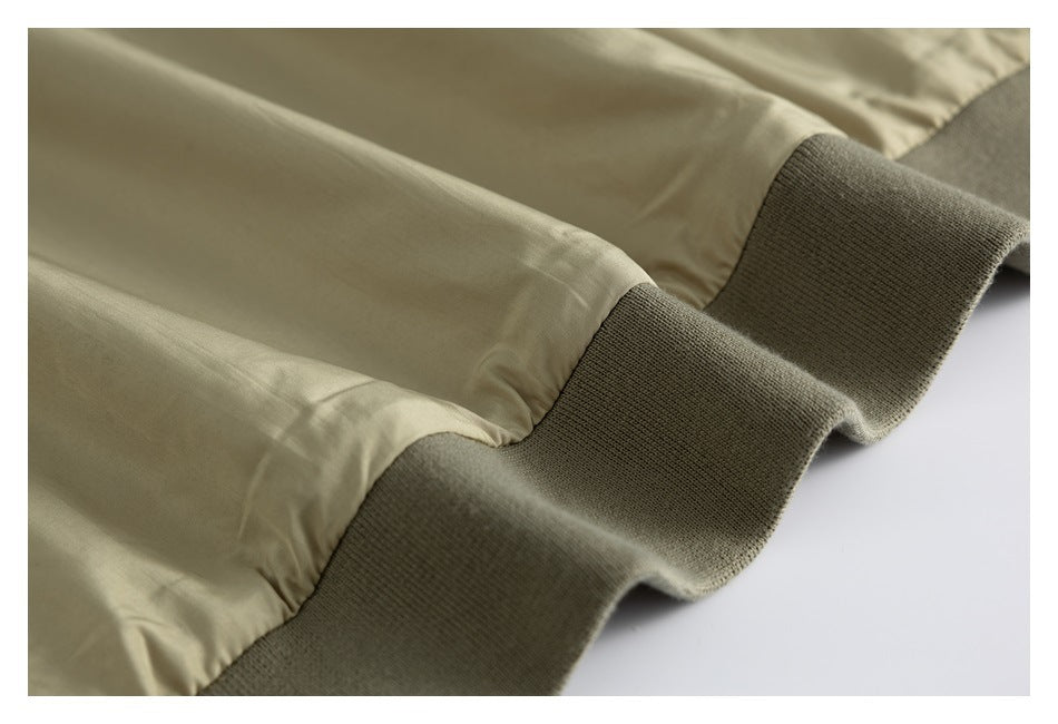 Close-up of beige garment sleeves ending in wide dark olive ribbed cuffs.