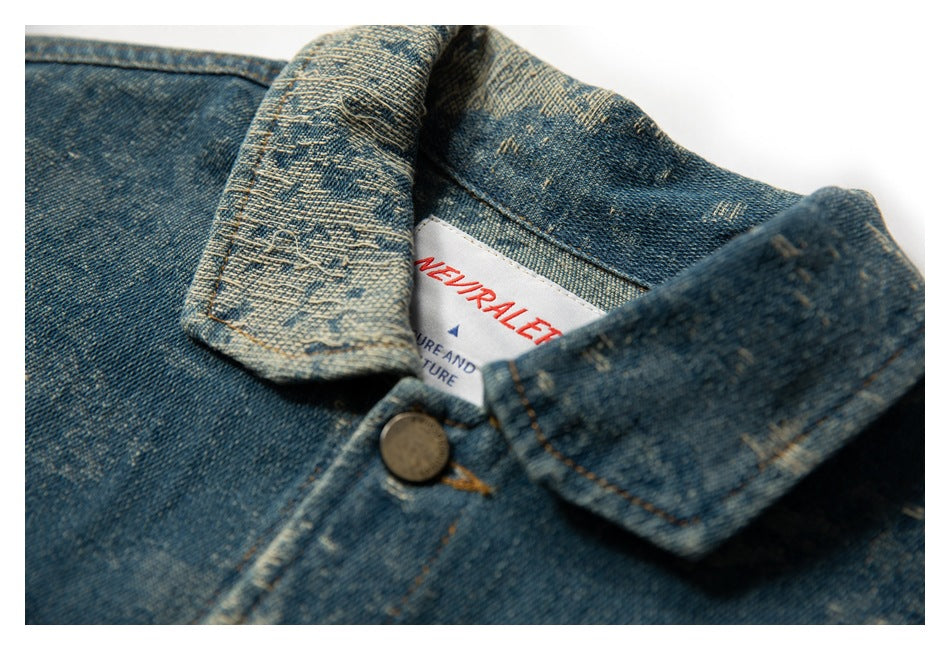 Close-up of the pointed collar and inner label of a distressed blue denim jacket.