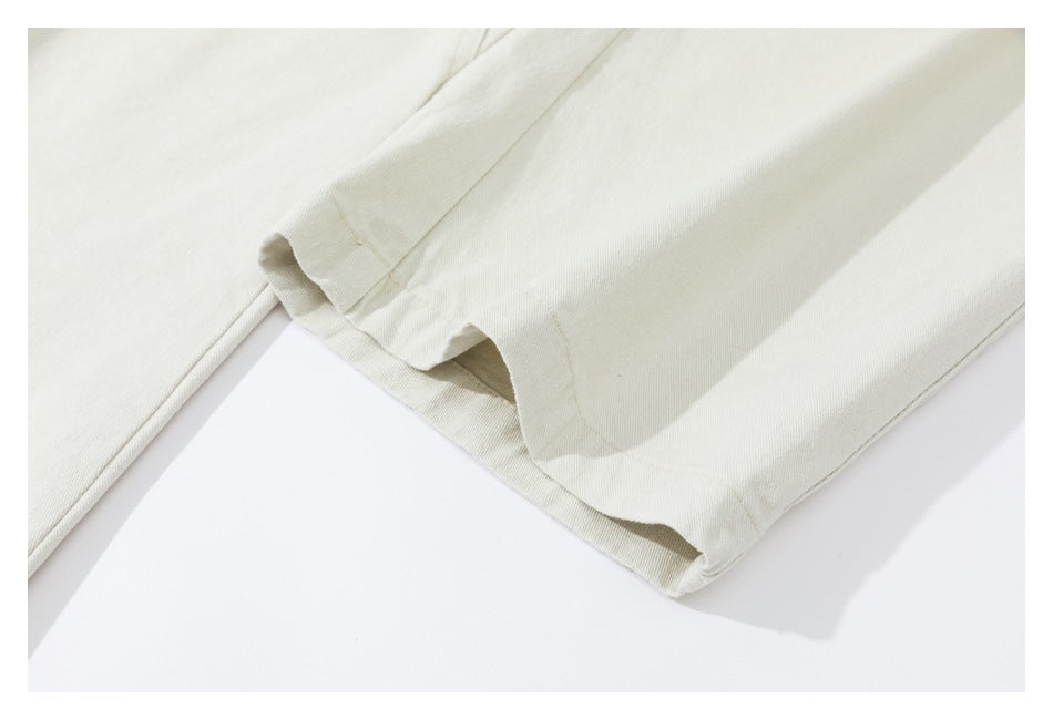 Close-up of the stitched hem on light beige trouser legs.
