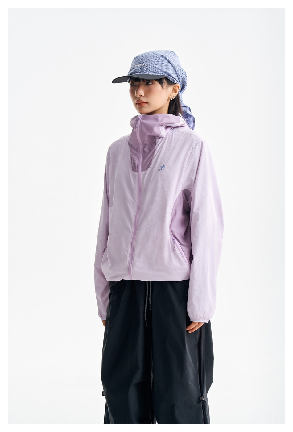 Three-quarter view of a model wearing a lilac hooded zip jacket and loose black pants.