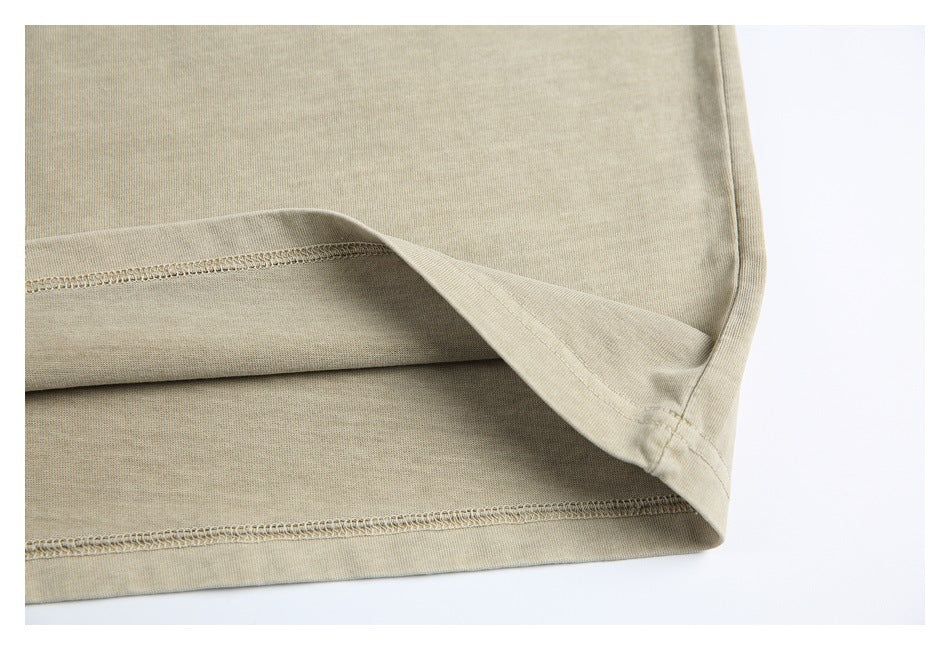 Close-up of the lower hem and inside stitching of a sand-beige T-shirt.